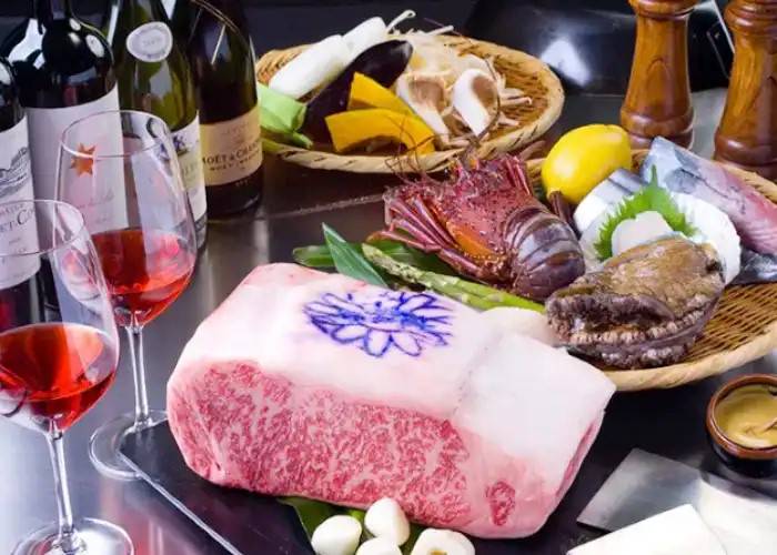 A premium slab of wagyu beef at Misono Kobe, surrounded by fine wine and other dishes.